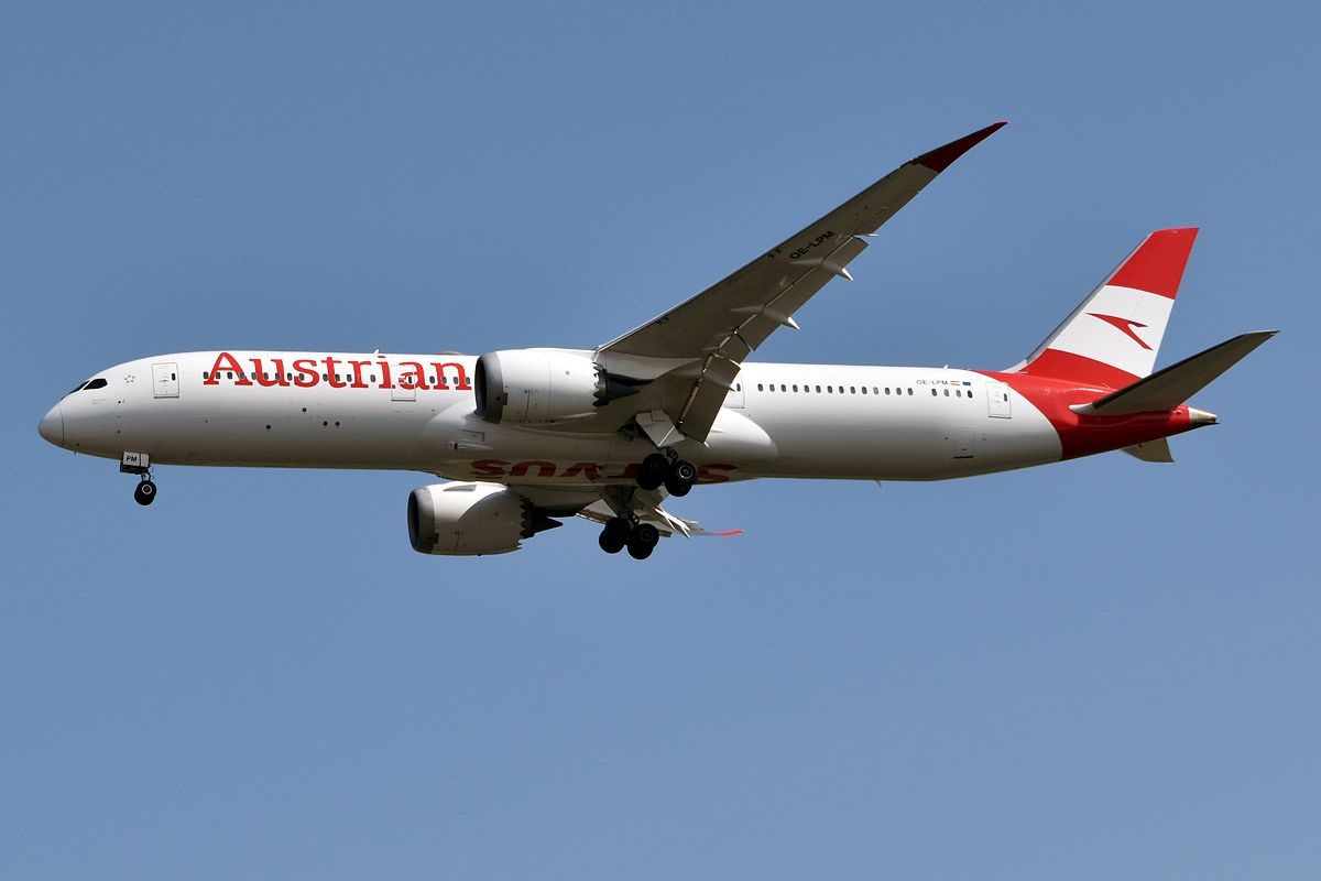 Austrian Airlines Boeing 777 in flight against a clear blue sky.
