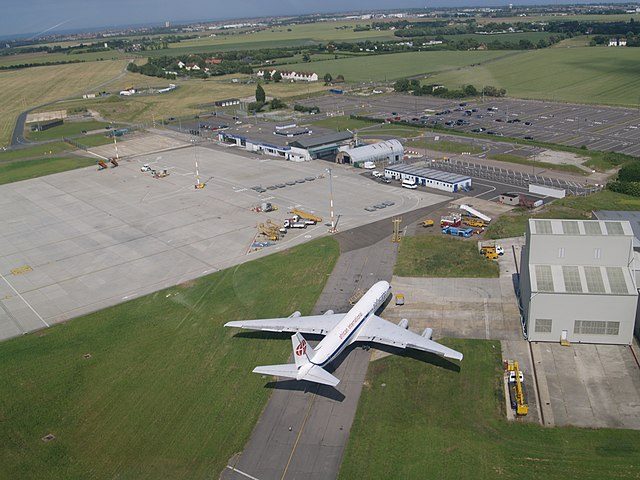 Aerial view of closed airport with parked aircraft and cargo facilities near rural English countryside