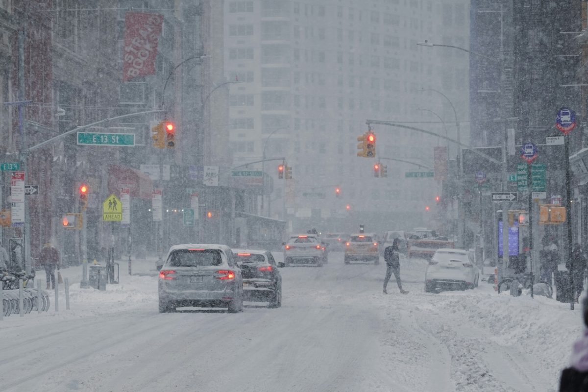 Snow-covered city street with heavy blizzard conditions and traffic lights visible