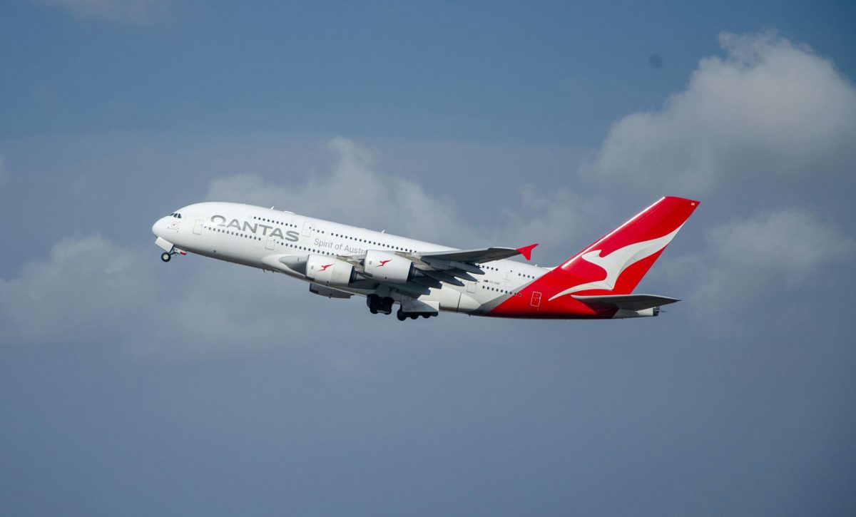 Qantas Boeing 787 Dreamliner flying against a blue sky with clouds.