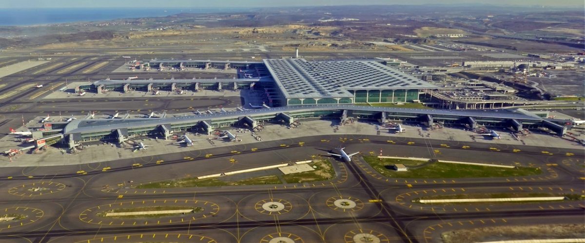 Aerial view of Istanbul Airport's modern terminal with distinctive blue roof and multiple runways