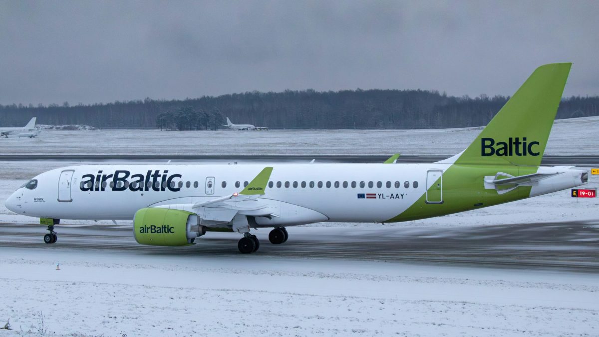 airBaltic Boeing 737 aircraft parked on snowy tarmac with forest background
