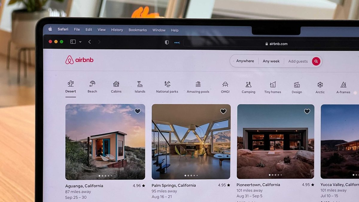 Laptop displaying the Airbnb website with search results for vacation rentals.