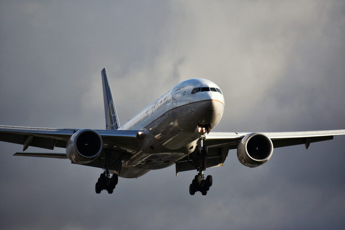 Boeing 777 airplane flying towards the viewer against a cloudy sky.