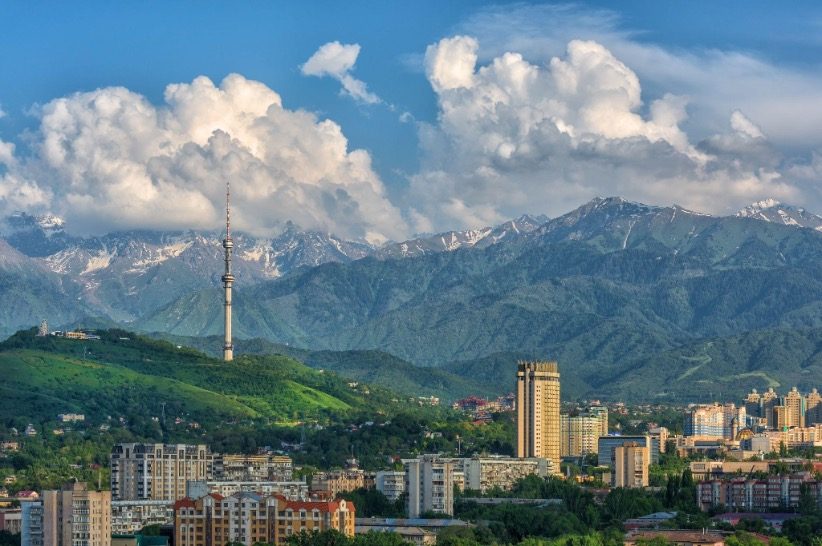 Almaty skyline with mountains and clouds, showcasing Kazakhstan's blend of urban and natural beauty.