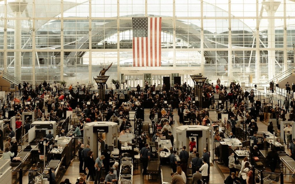 Crowded airport terminal with masses of travelers and long security screening lines
