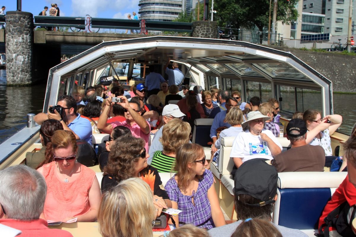Crowded tourist boat full of visitors on Amsterdam canal