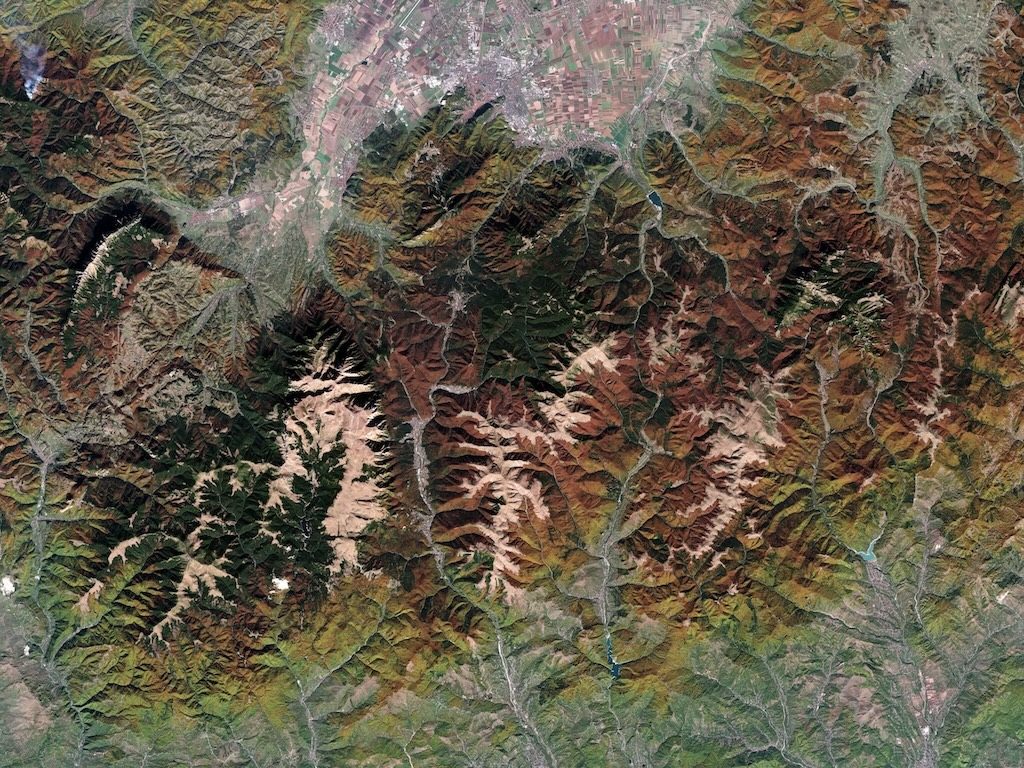 Satellite view of autumn foliage across mountains and valleys.