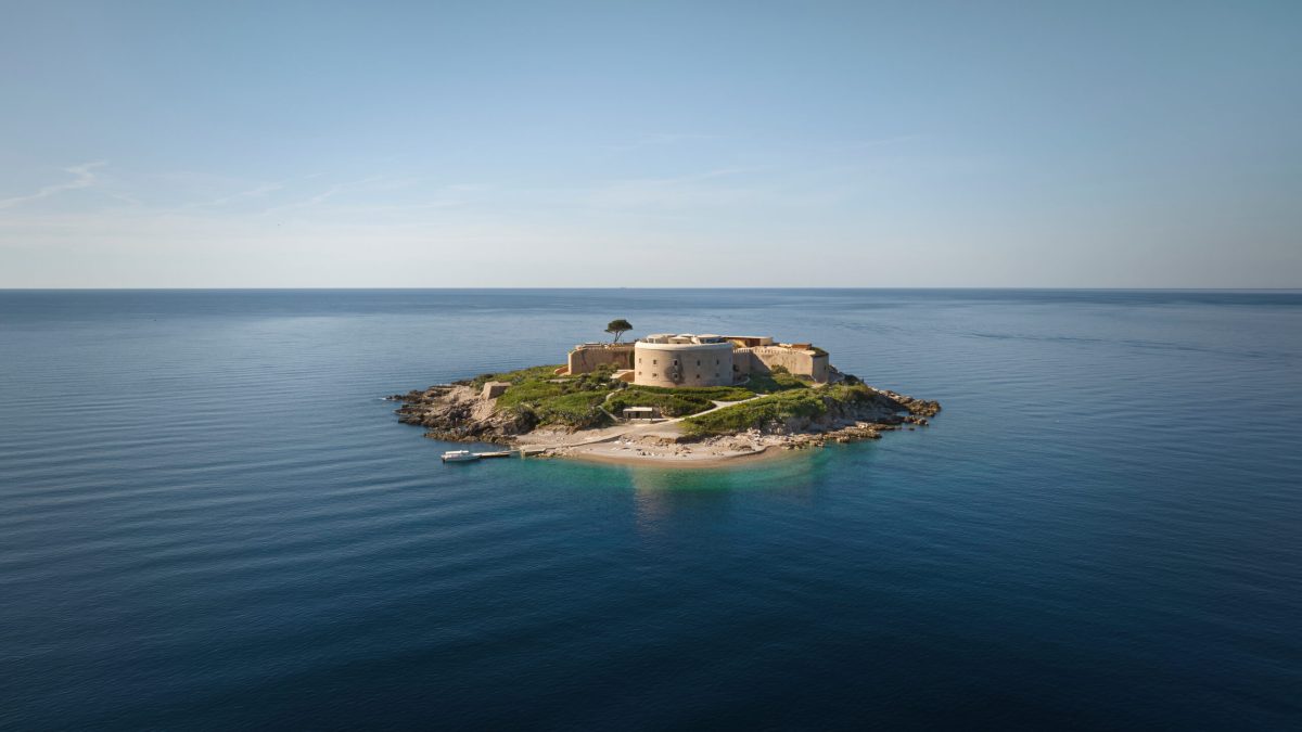 Fortified island with sandy beach and restored stone fortress surrounded by turquoise Adriatic waters