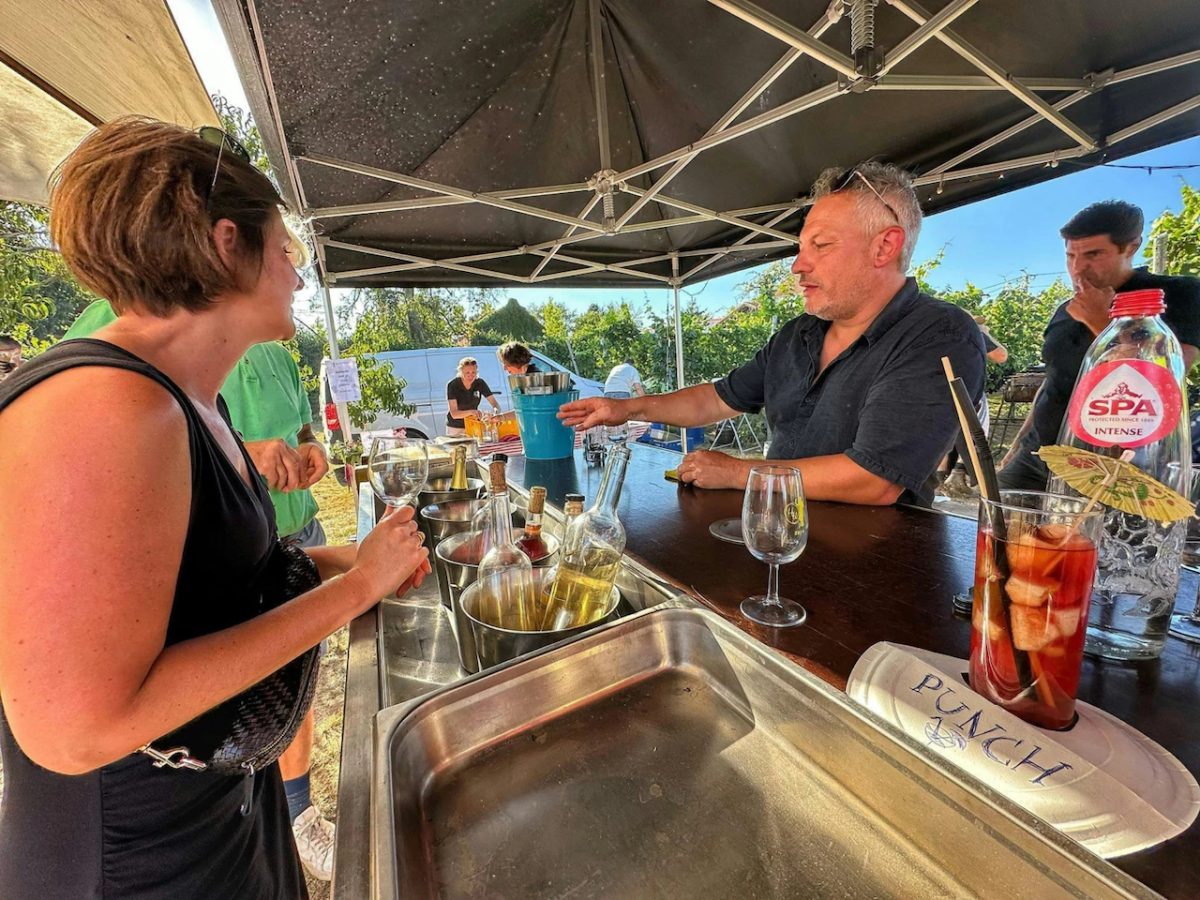 Bartender pouring wine at outdoor tasting event under tent canopy