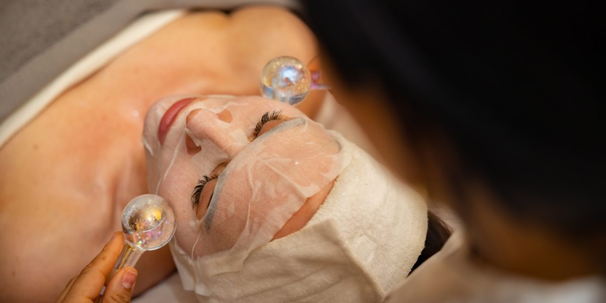 Facial treatment with clear gel application on client's face during spa procedure