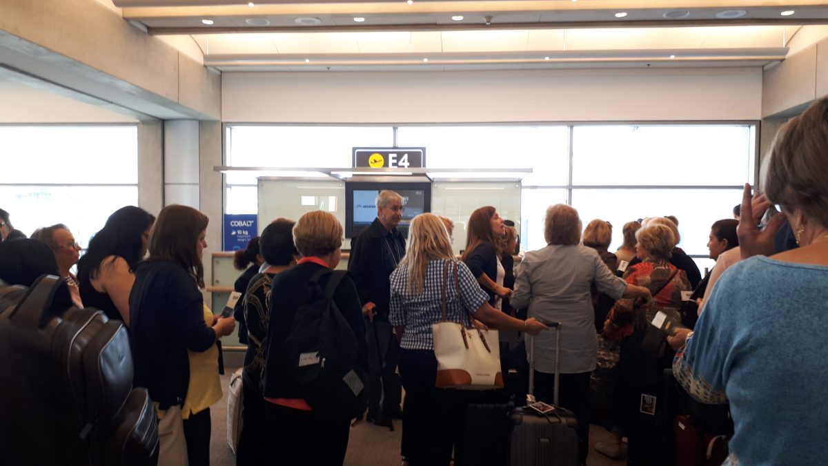 Crowded airport gate area with frustrated passengers waiting during flight disruption