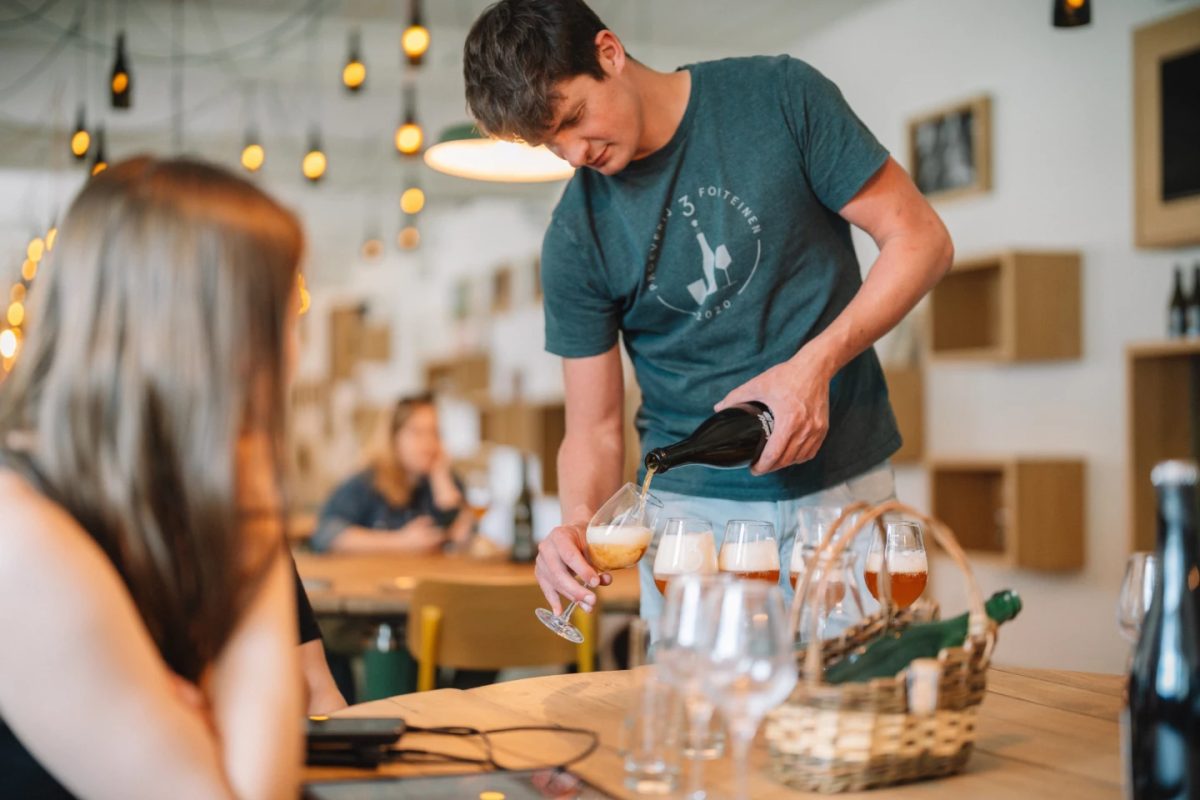 Brewery worker pours lambic beer for a tasting session.