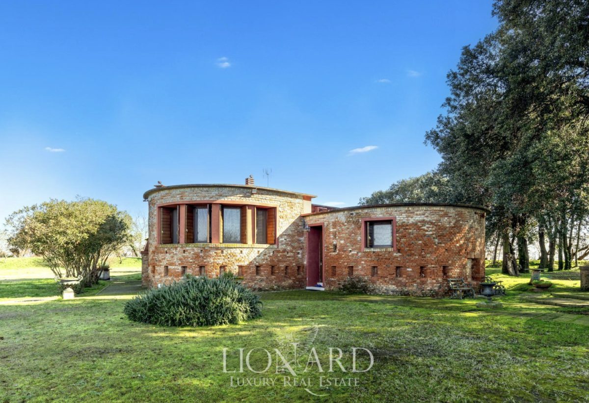 Brick building with tower on grassy island surrounded by trees