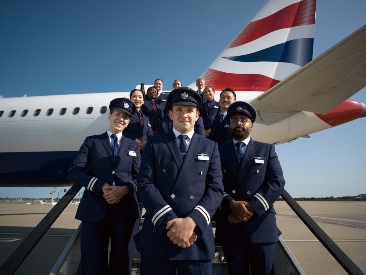 British Airways pilots in uniform standing in front of aircraft with tail visible