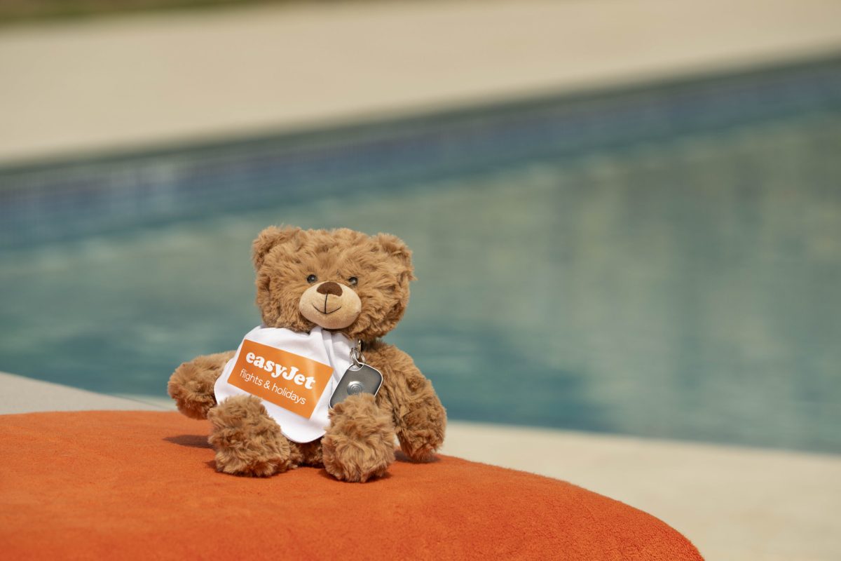 Brown teddy bear with easyJet branding sitting poolside