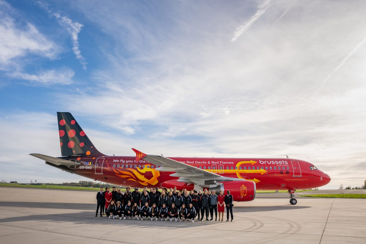 Brussels Airlines red Trident aircraft with football design on tarmac with team in front