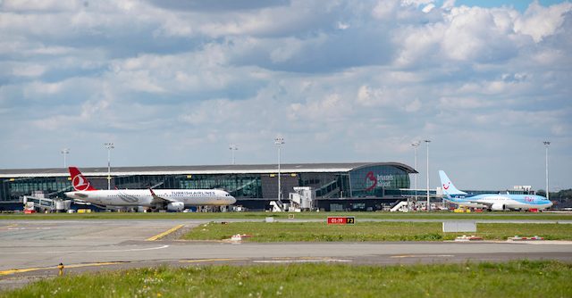 Brussels Airport terminal with aircraft parked at gates under cloudy sky
