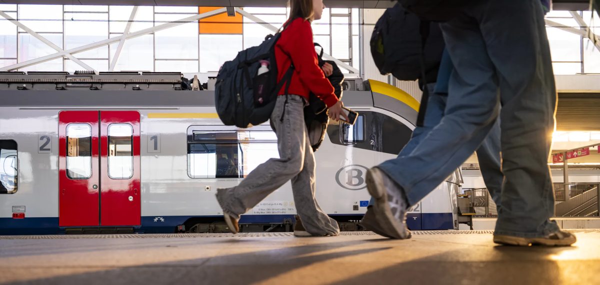 Passengers boarding a modern train at Brussels Airport station with red doors visible