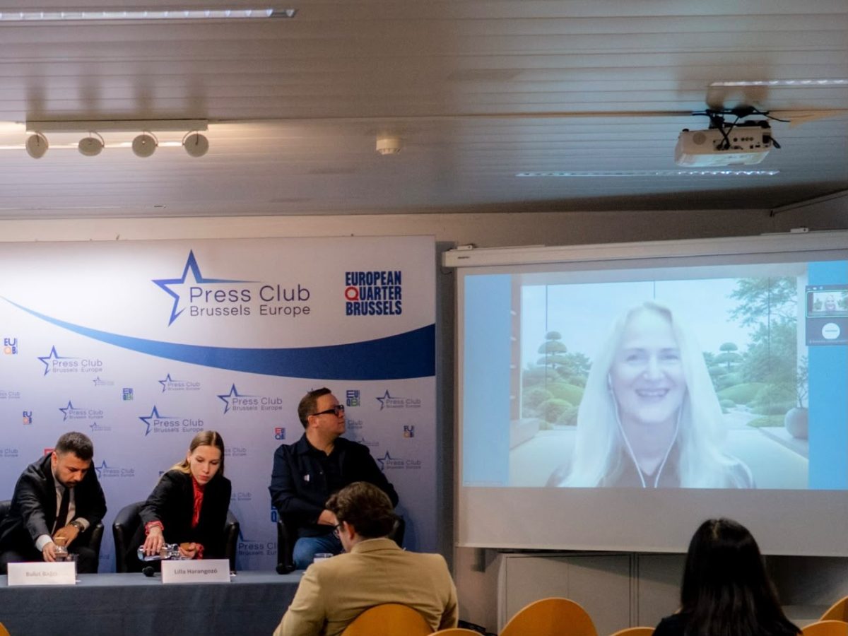 Brussels Press Club with a speaker on a screen, hinting at international collaboration.