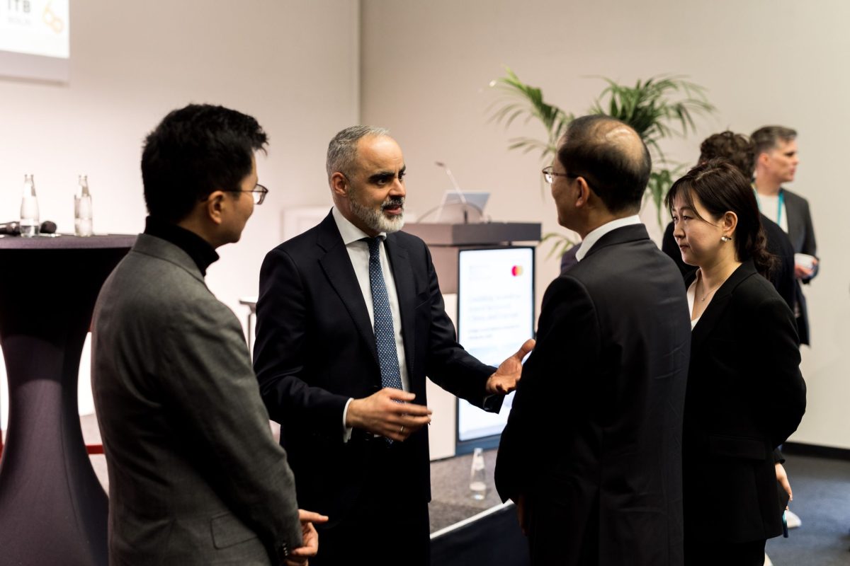 Business professionals in formal attire discussing travel solutions at ITB Berlin 2026