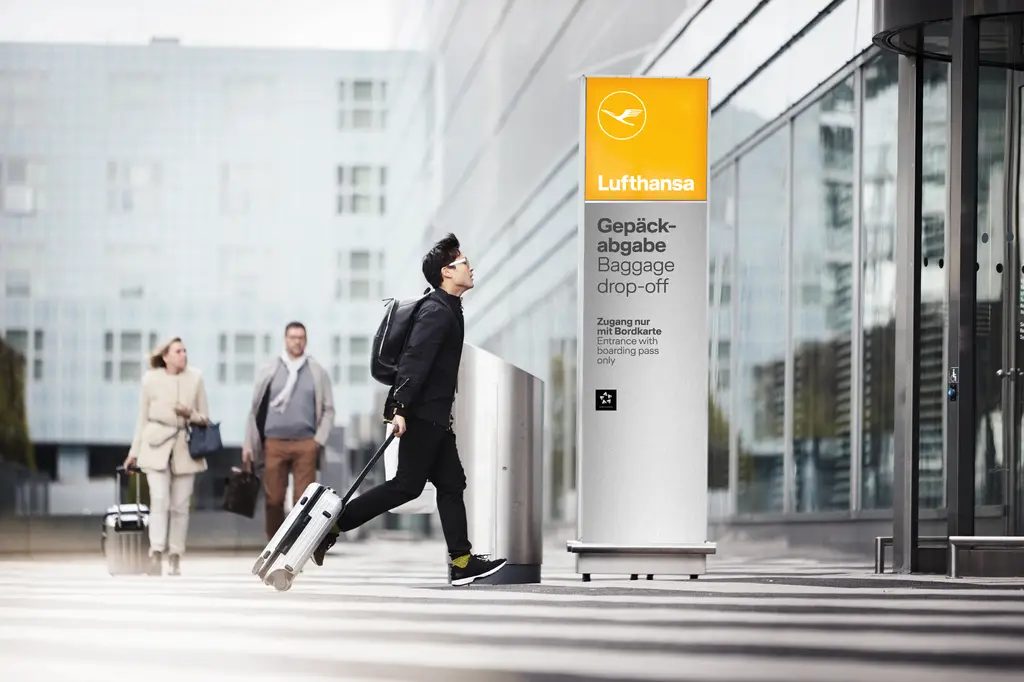 Business travelers walking through modern airport terminal with Lufthansa signage visible