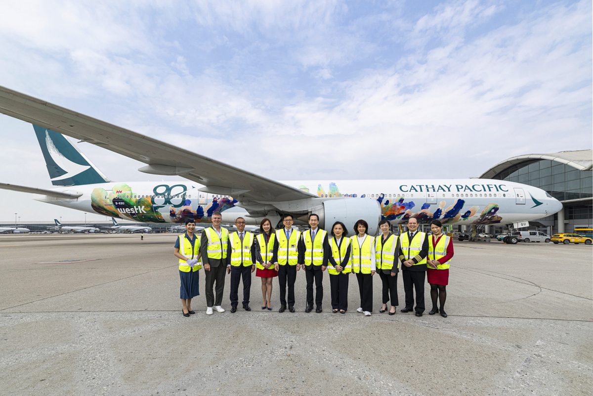 Cathay Pacific staff in safety vests stand before aircraft with Spirit of Hong Kong livery