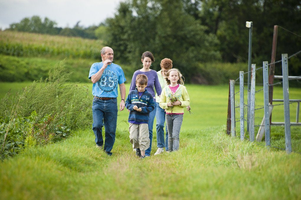Children running through a grassy field in Tervuren during a nature hike