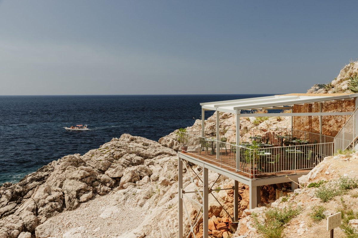 Coastal wooden deck overlooking rocky Adriatic shoreline with small boat in water