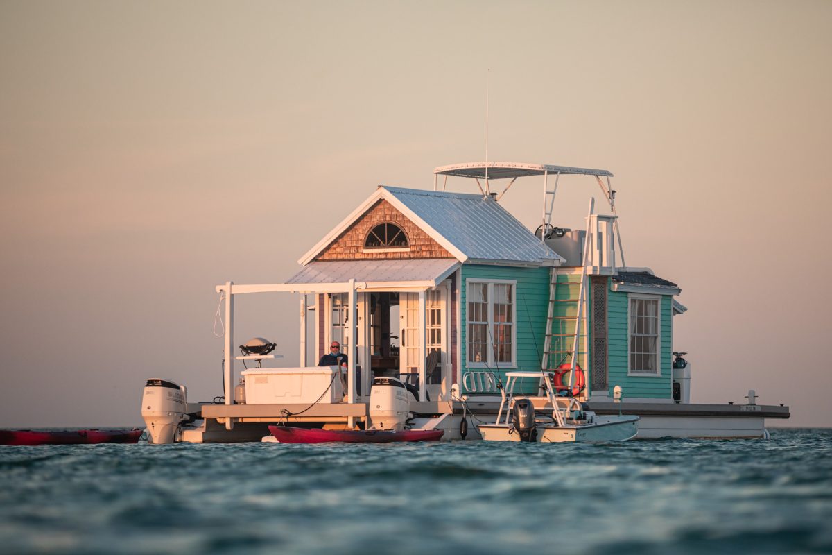 Colorful houseboat floating on calm turquoise water at sunset
