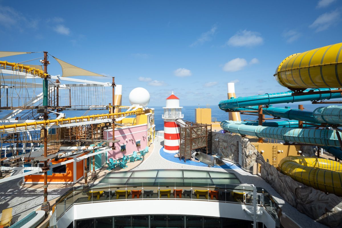 Colorful water slides and funnel on a modern cruise ship deck under blue sky