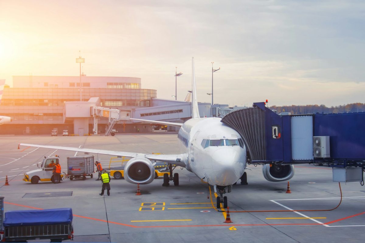 Commercial aircraft being serviced at airport gate during golden hour with ground equipment