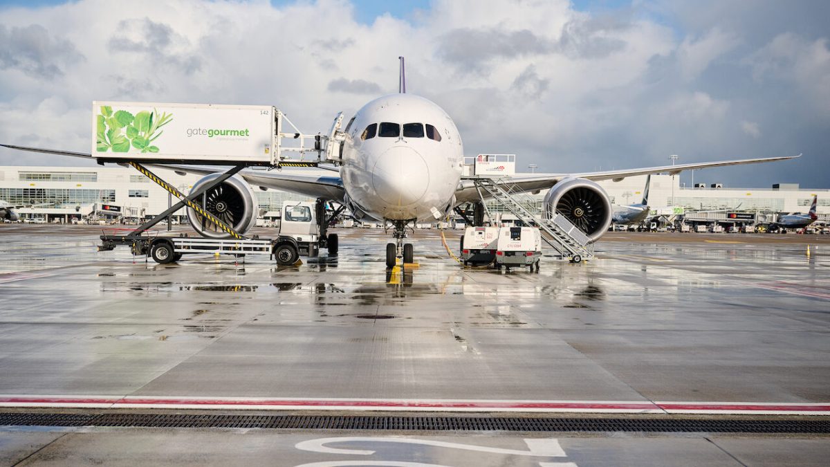 Commercial aircraft being serviced at Brussels Airport with ground equipment and wet tarmac