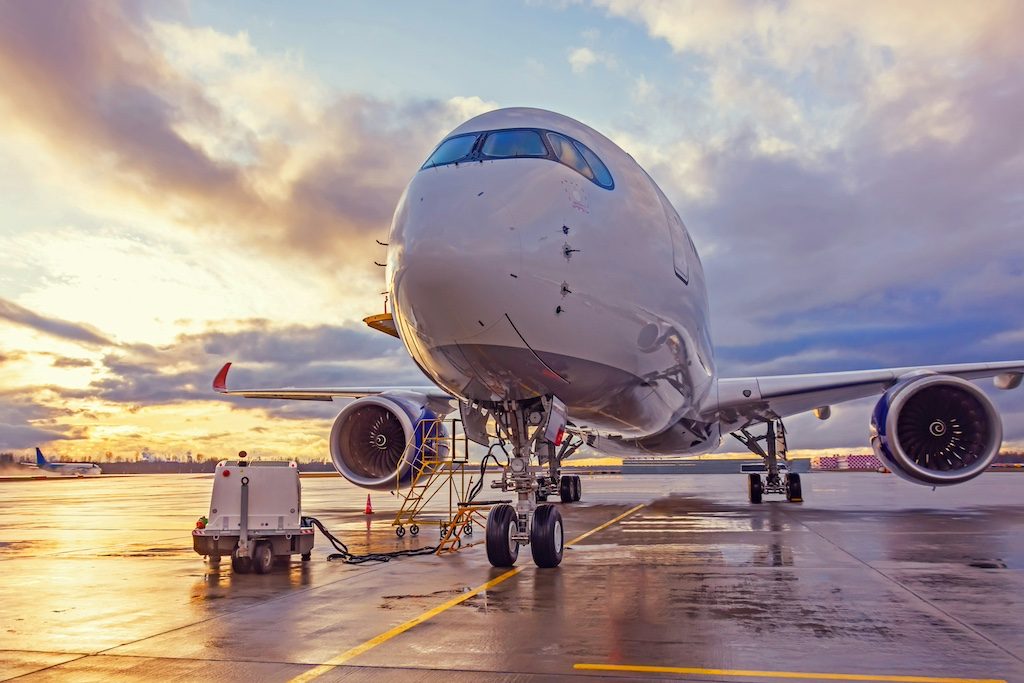 Commercial aircraft parked at airport terminal during golden hour sunset