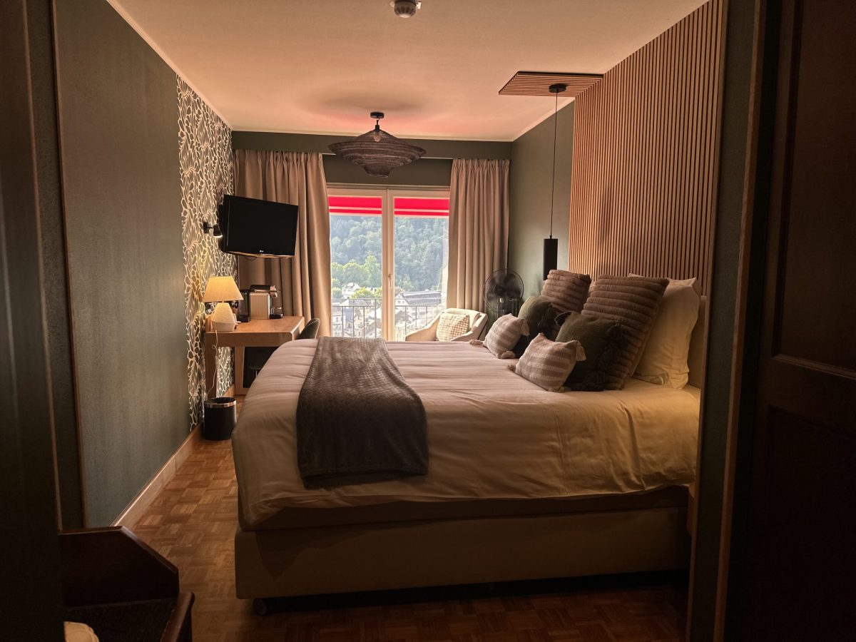 Cozy bedroom with large bed, warm lighting, and window overlooking Ardennes landscape