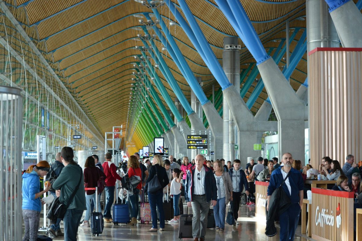 Crowded airport terminal with passengers and luggage moving through modern architecture