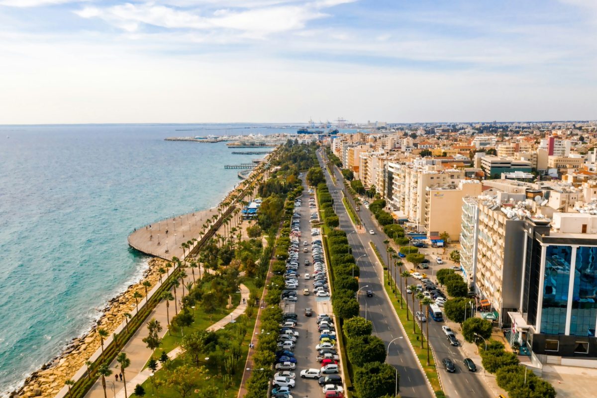 Aerial view of a Mediterranean coastal city with turquoise waters and tree-lined promenade