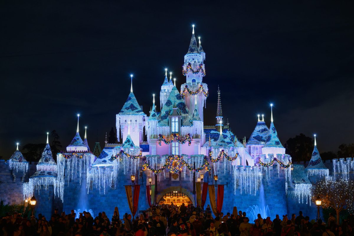 Disneyland Castle illuminated in blue and purple holiday lights at night