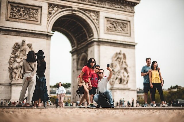 Diverse tourists enjoying Arc de Triomphe in Paris, taking photos and exploring