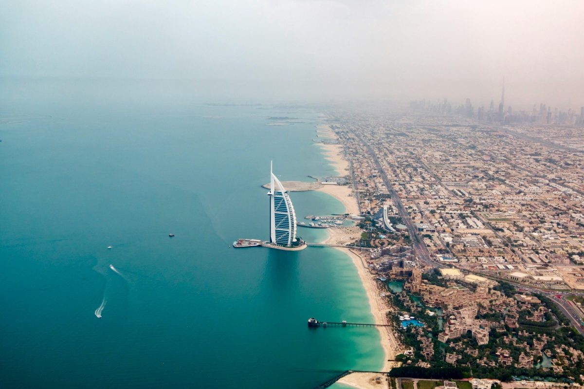 Aerial view of Dubai's Burj Al Arab hotel and coastline with turquoise waters
