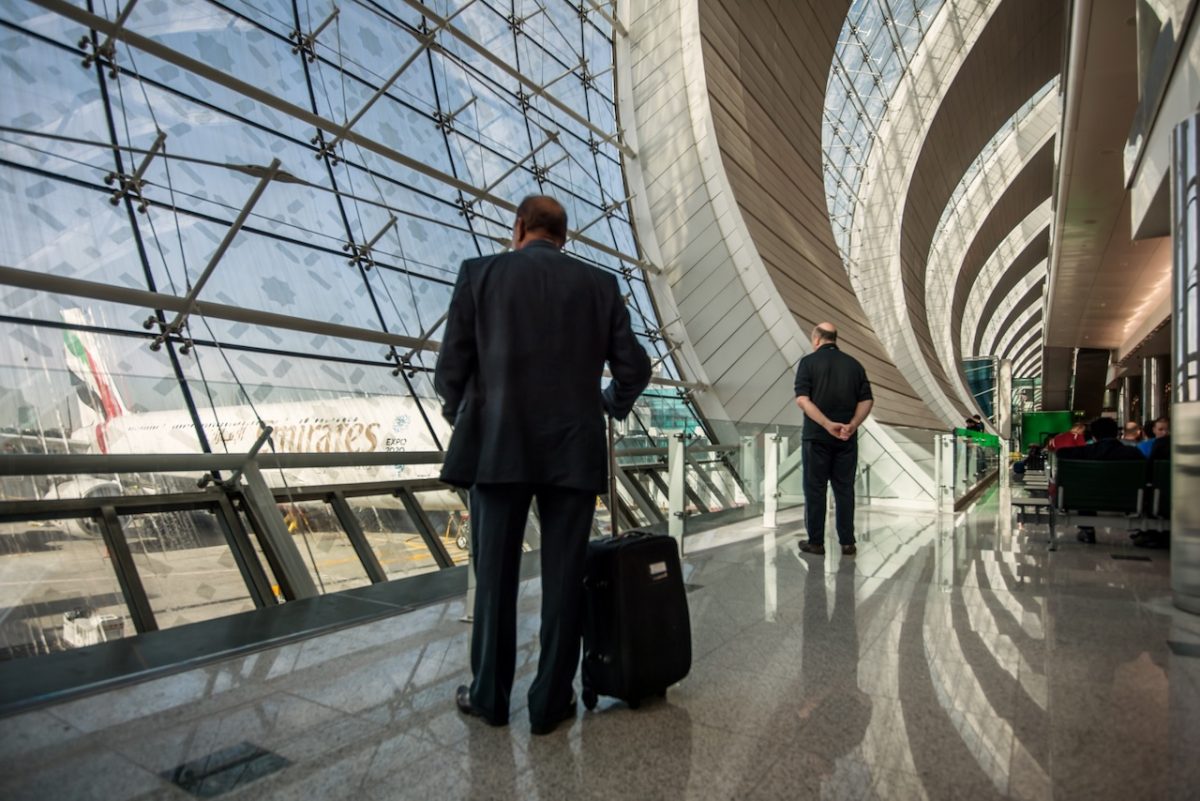 Business traveler with luggage in modern airport terminal with curved architecture