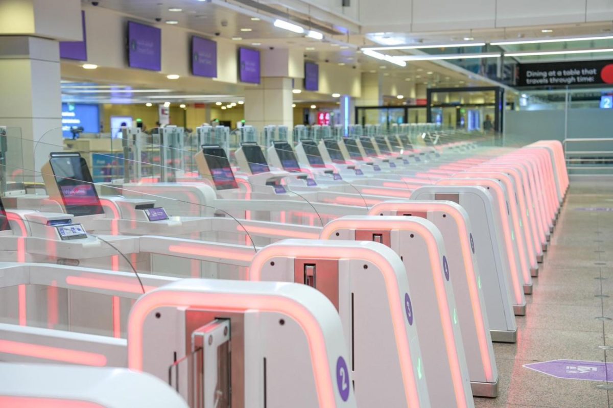 Row of pink and white biometric gate terminals at Dubai International Airport