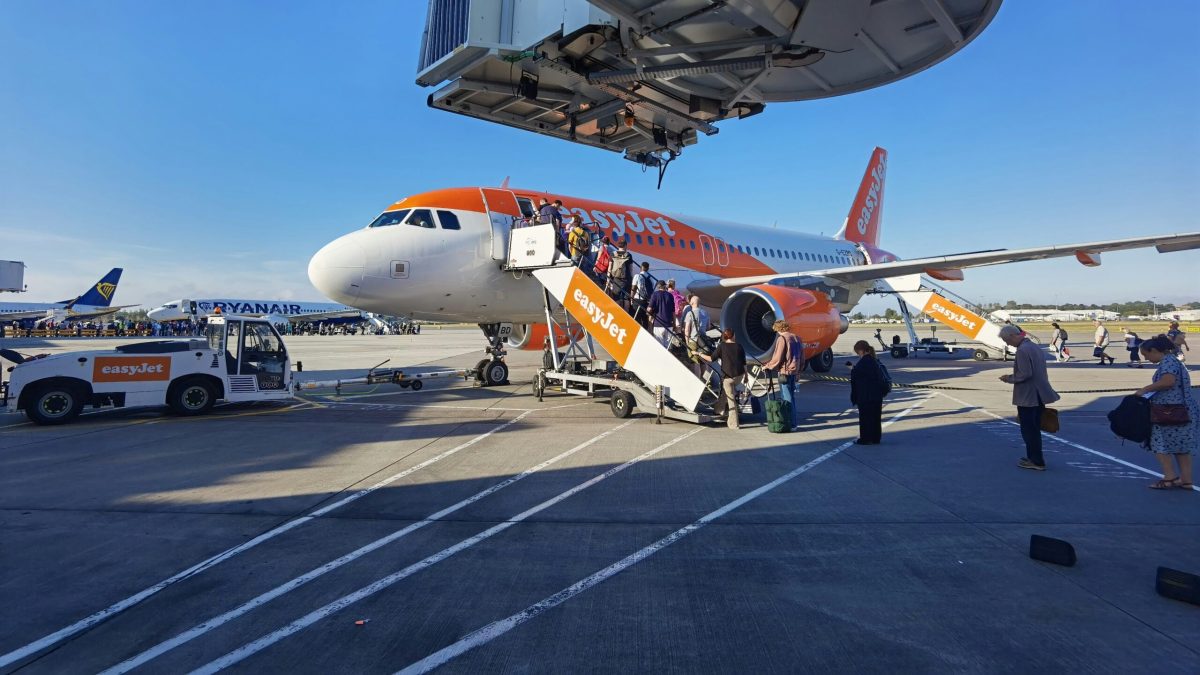 EasyJet aircraft at airport terminal with passengers boarding via stairs