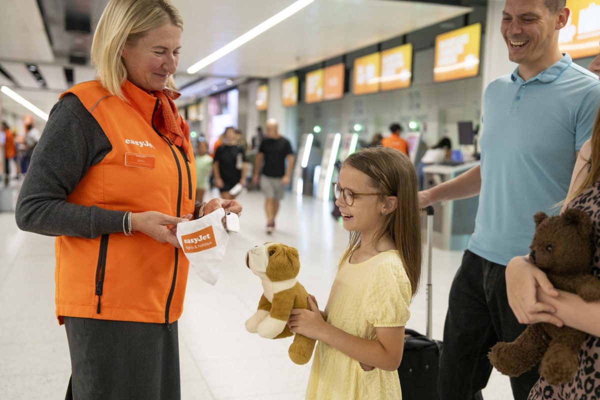 easyJet staff member handing teddy bear tracker to young girl at airport counter