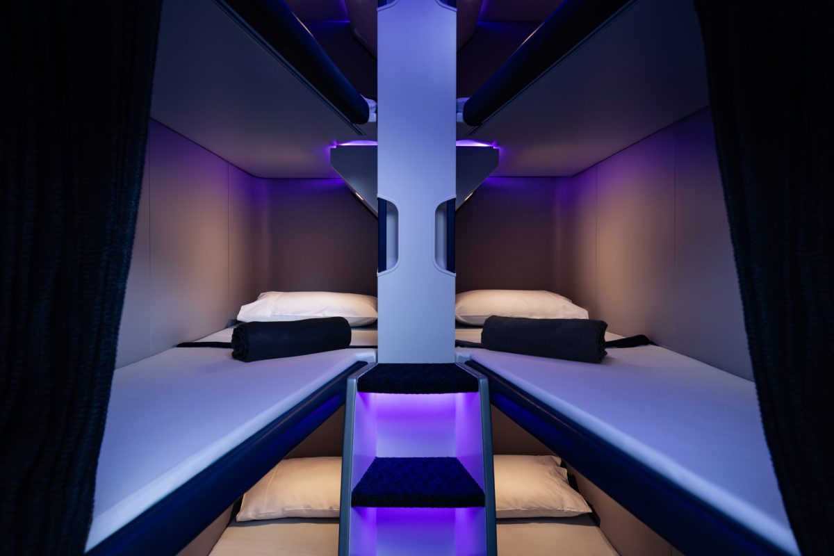 Economy Skynest bunk beds stacked in aircraft cabin with purple ambient lighting