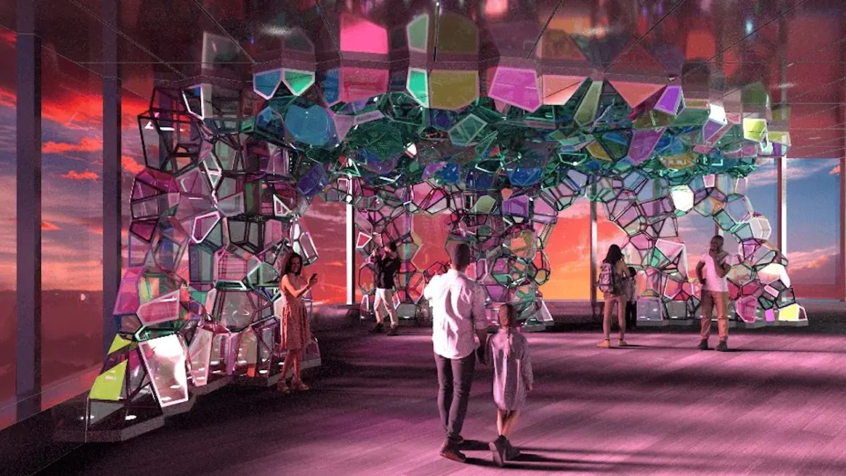 Visitors explore a colorful kaleidoscope art installation with mirrored geometric shapes at Edge NYC