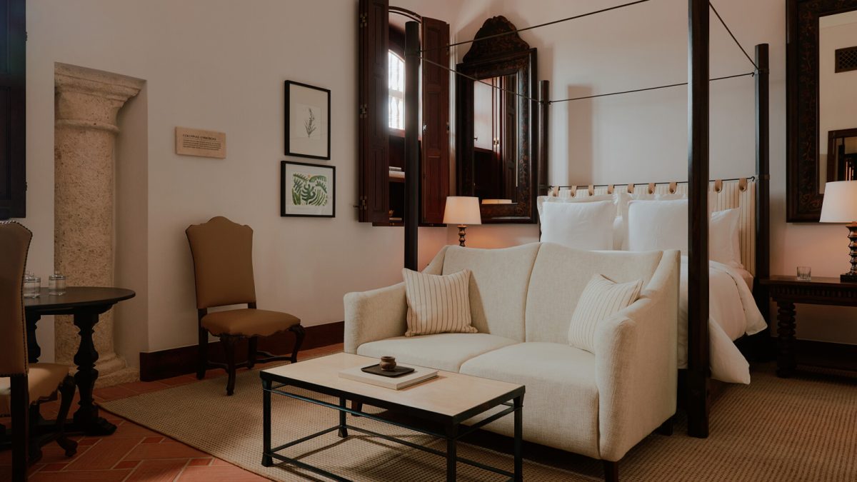 Elegant Four Seasons suite with canopy bed, cream seating area, and colonial-style furnishings