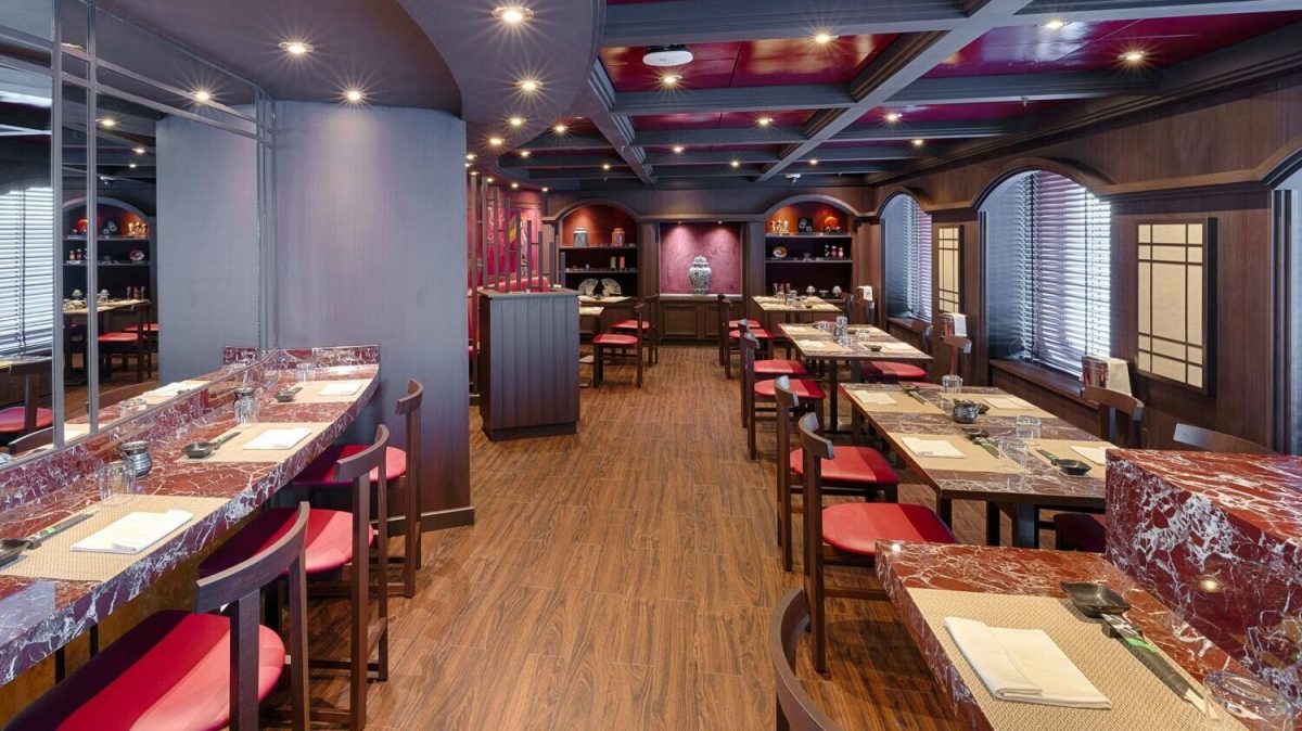 Elegant MSC Yacht Club dining venue with burgundy accents and wooden furnishings