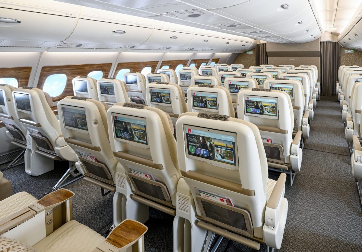 Emirates aircraft cabin with rows of seats featuring individual seatback monitors