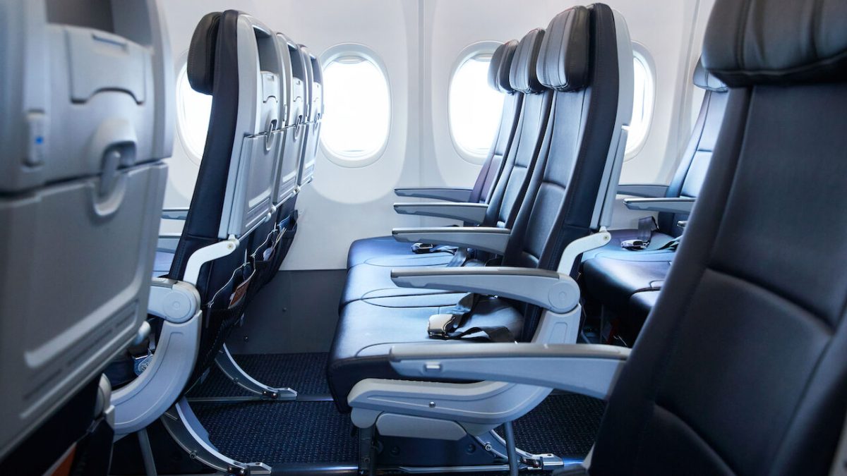 Empty airplane cabin seats in a row with windows visible in background